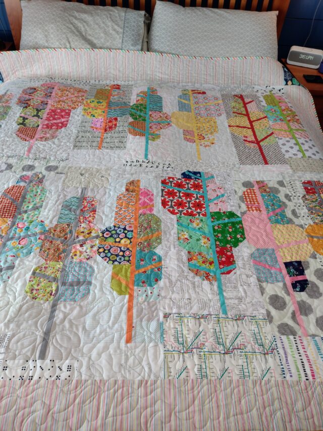 Scrappy quilt pattern of many trees in colourful fabrics.